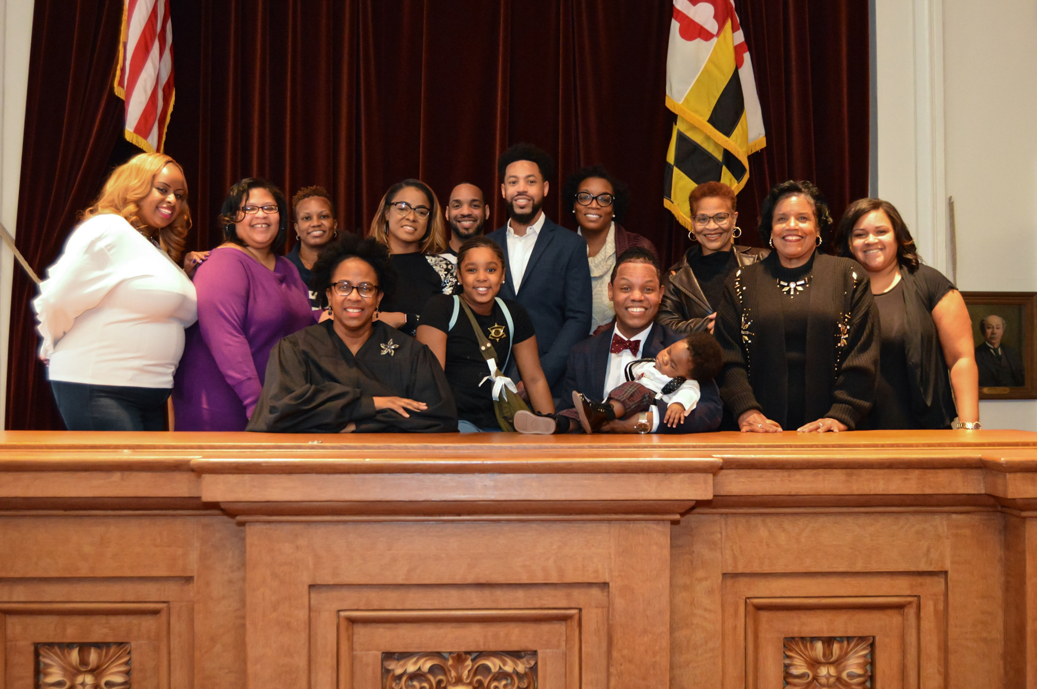 A smiling group gathered with a parent and child in a courtroom